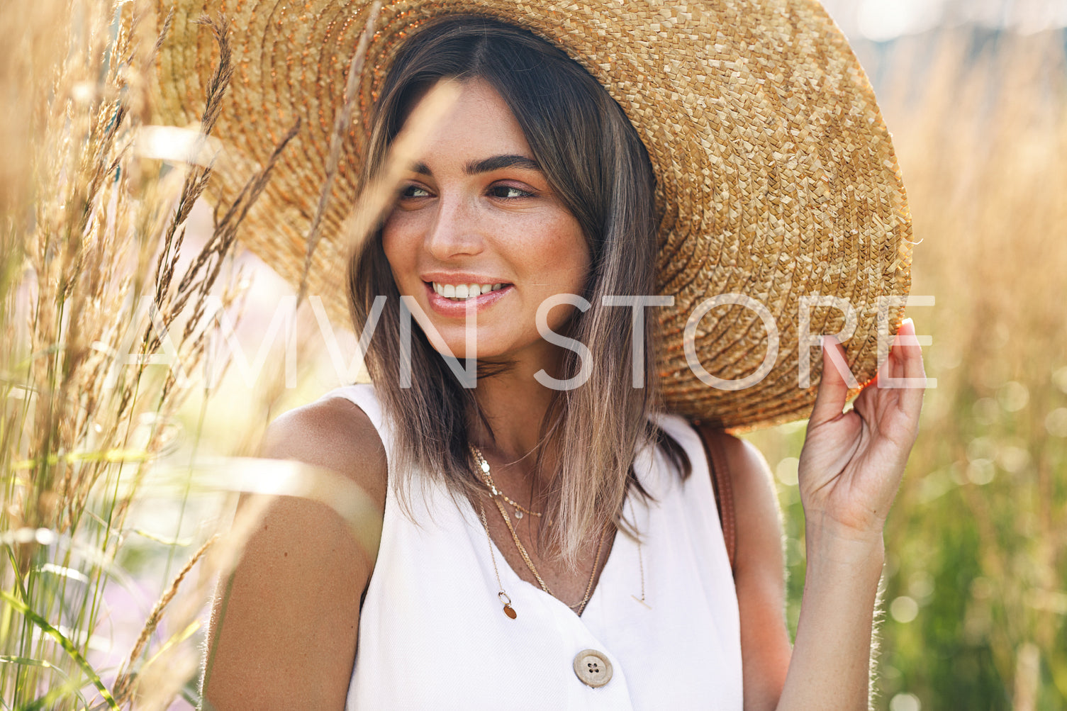 Beautiful caucasian woman holds her hat and looking away while standing outdoors	