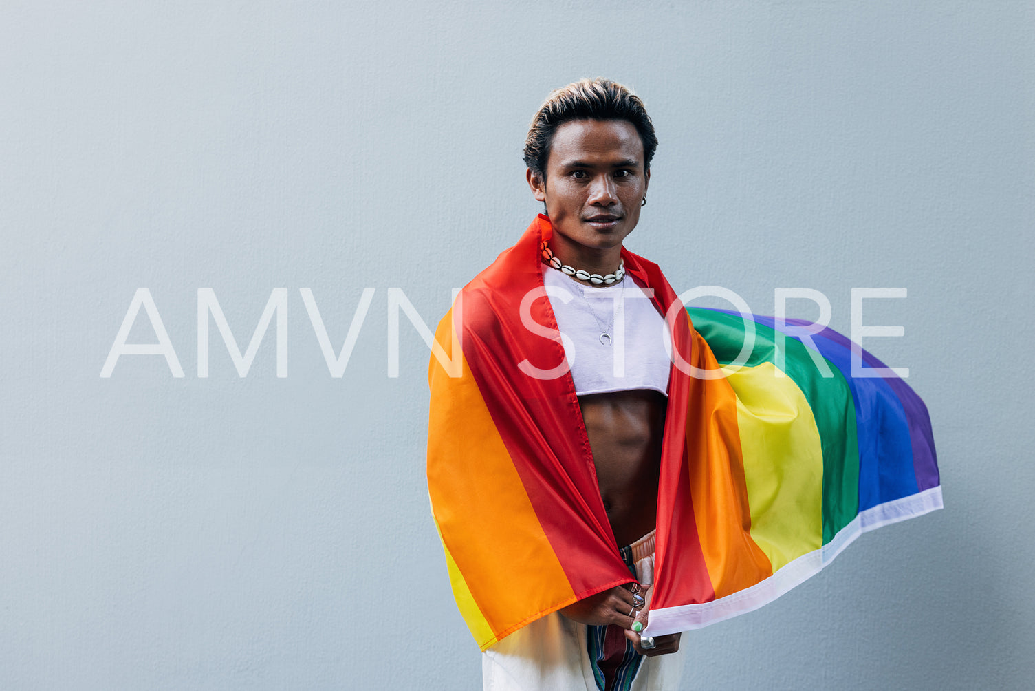 Portrait of a young guy with lgbt flag posing outdoors at grey wall