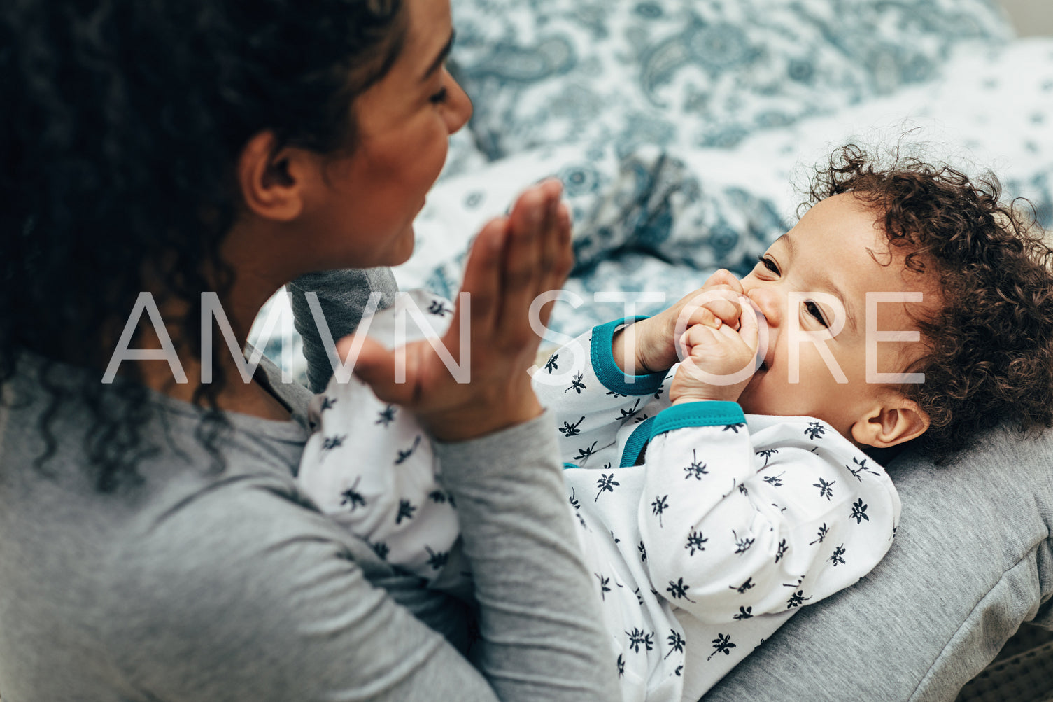 Mother holding baby on her lap and playing. Happy little boy looking at mother.	