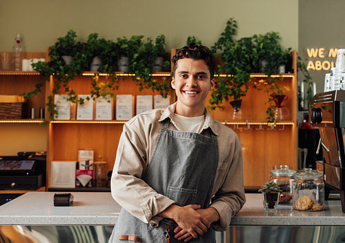 Smiling male waiter in an apron. Portrait of a handsome barista at the counter.