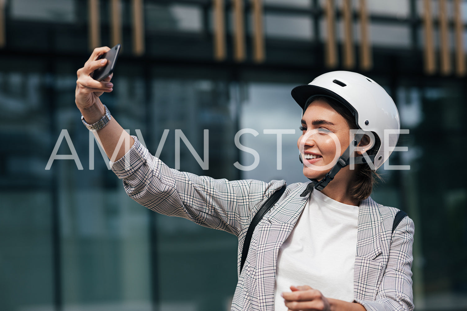 Smiling female wearing safety helmet taking a selfie. Young businesswoman in a white helmet in front of a building. 