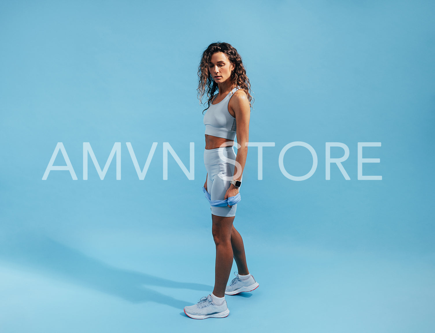 Fit female taking a break during workout on blue backdrop