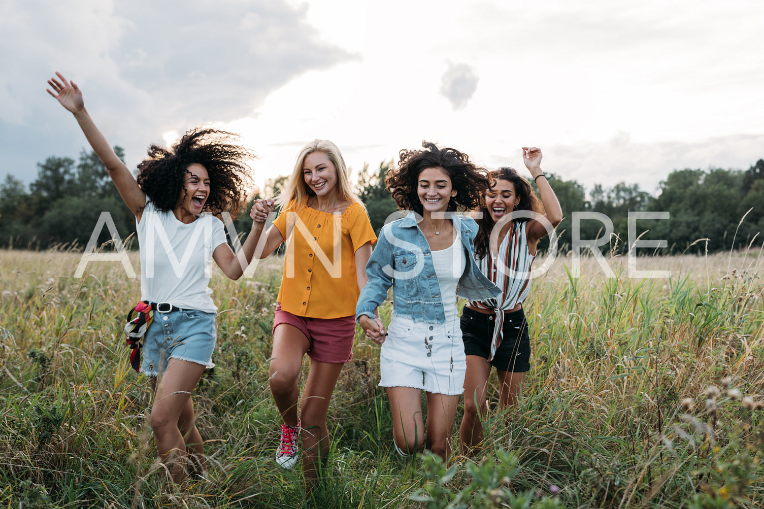 Four laughing women enjoying summer vacation. Happy friends running on the field.