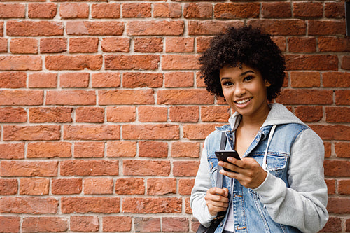 Smiling girl holding mobile phone, looking at camera