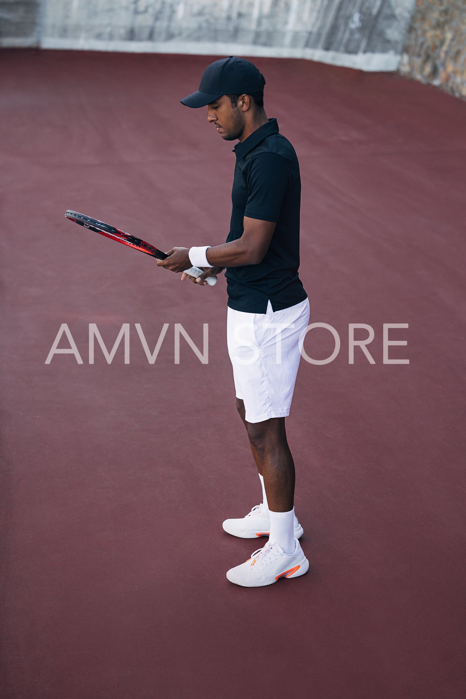 Side view of a male tennis player in sportswear adjusting his racket