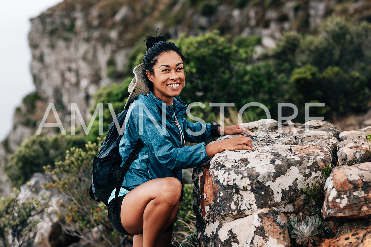 Smiling woman hiker in sports clothes taking a break and looking away during climbing