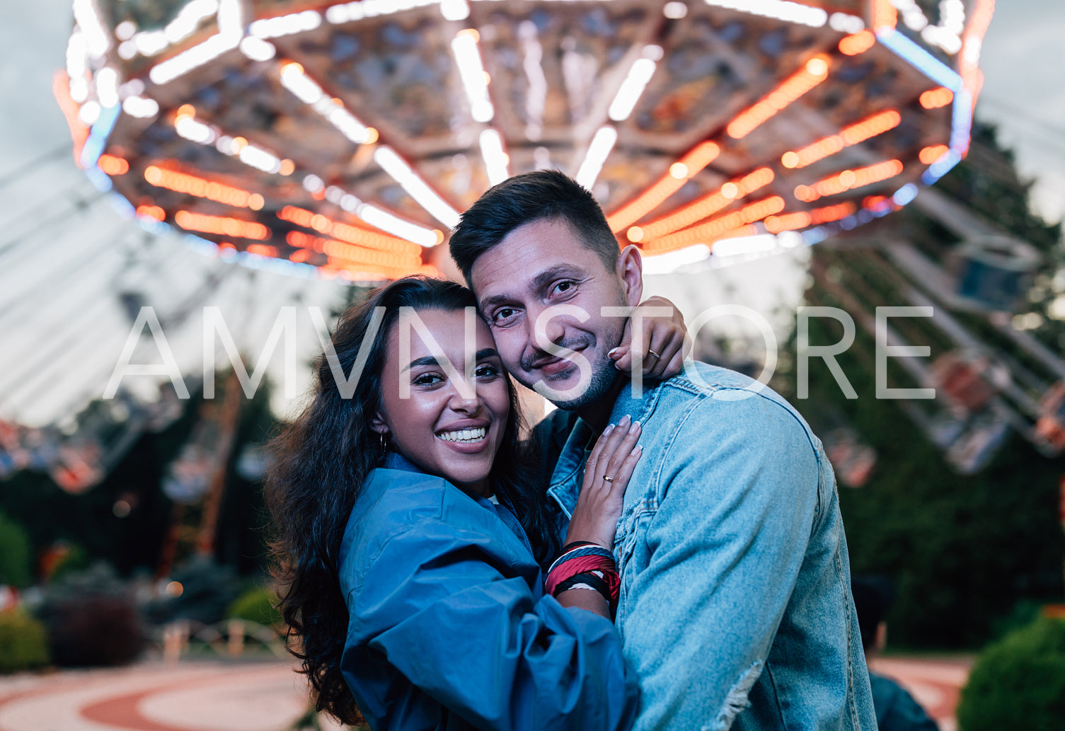 Boyfriend and girlfriend looking at camera while embracing in amusement park