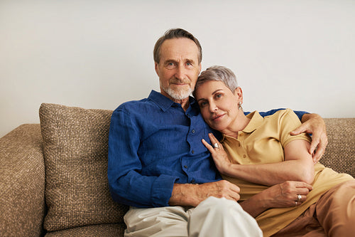 Senior couple embracing on a sofa. Affectionate people hugging at home.