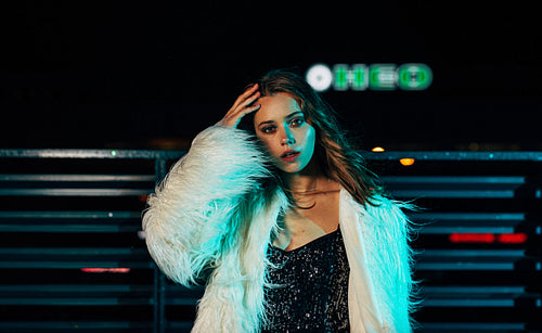 Portrait of a young woman posing outdoors at night wearing stylish clothes