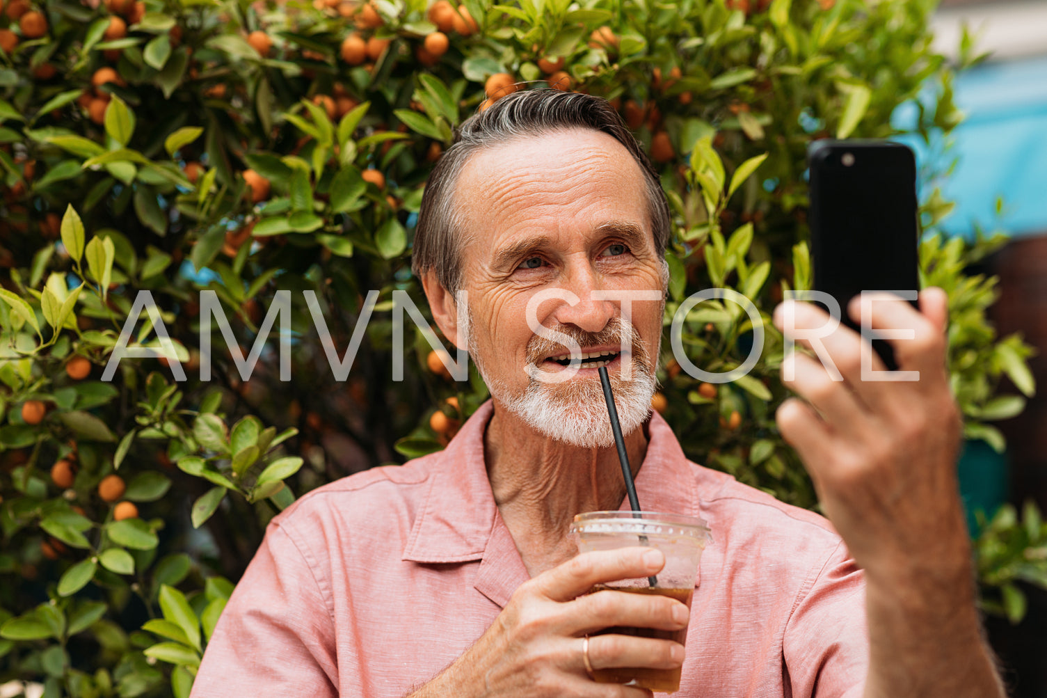 Smiling senior male taking selfie while drinking a smoothie in the park