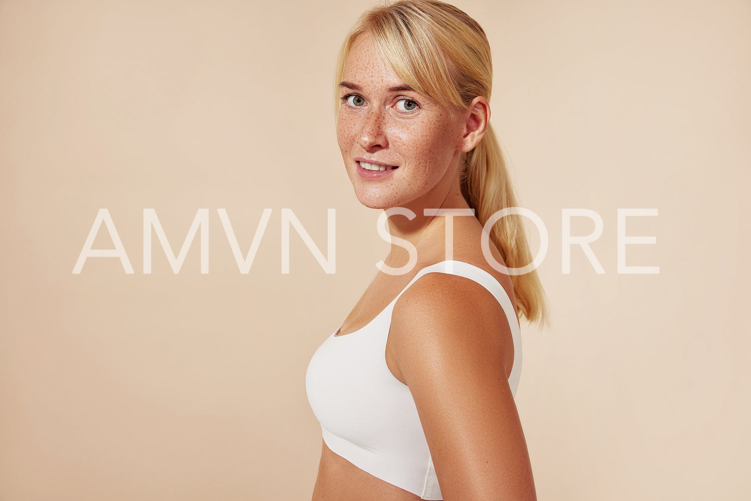 Beautiful blond woman with freckles posing in studio against pastel background