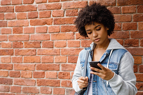 Teenage girl chatting on the mobile phone. Young woman checking social media outdoors.