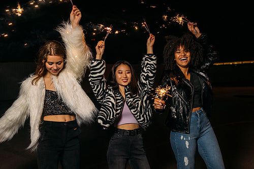 Happy stylish girls walking together at night and having fun