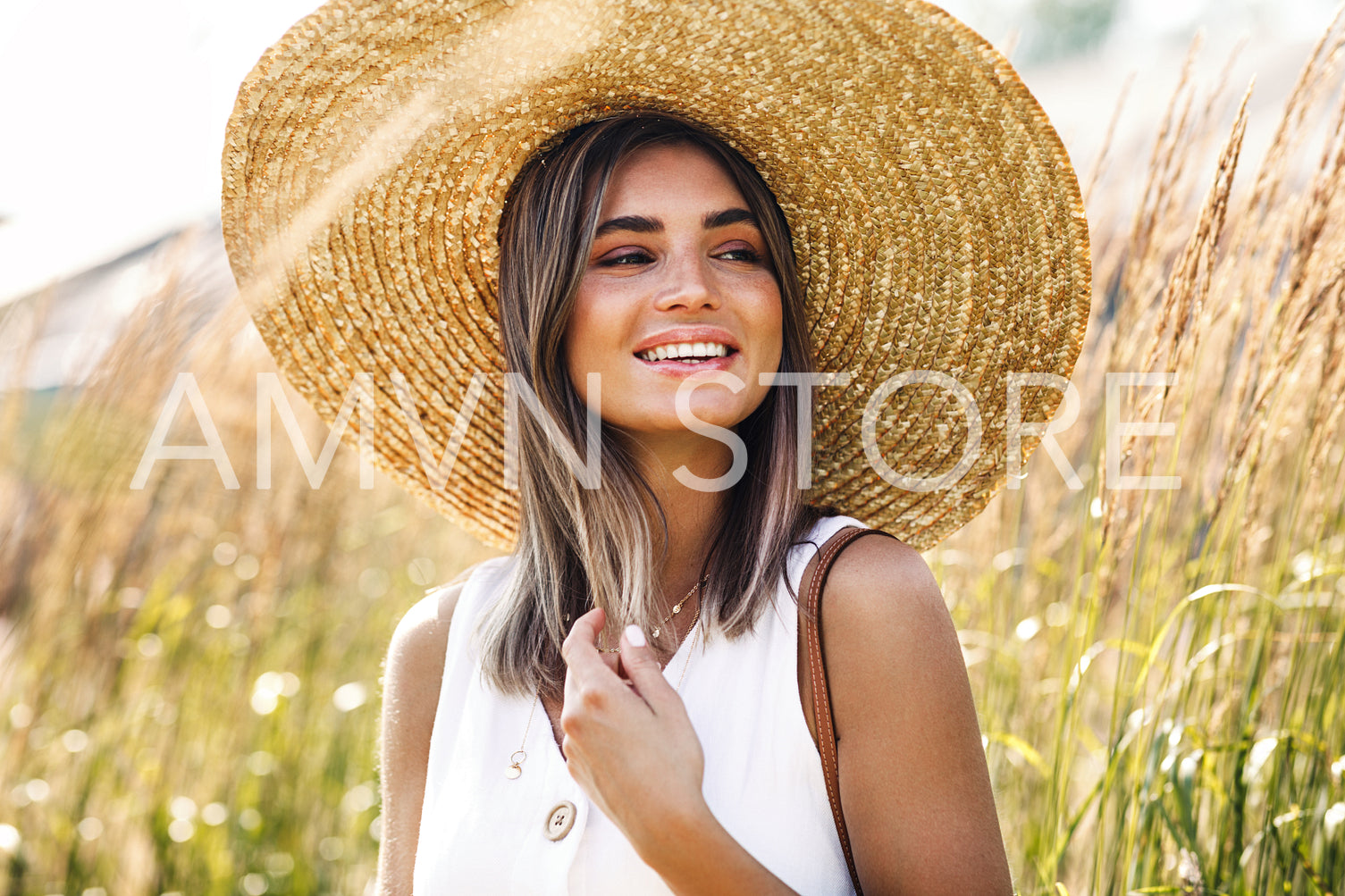 Beautiful smiling woman wearing straw hat while standing on a wheat field	