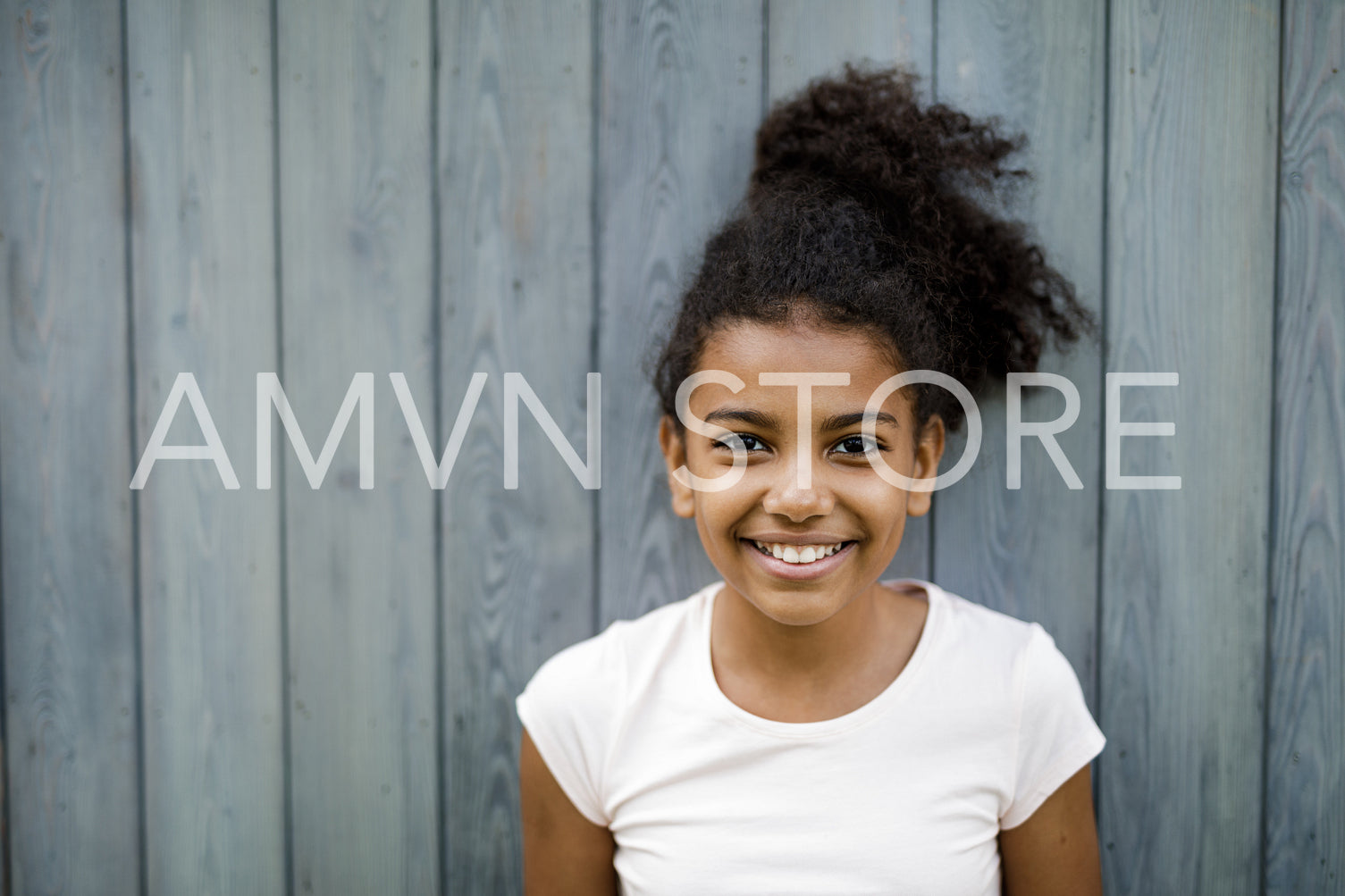 Horizontal shot of happy cute girl standing at wall outdoors	