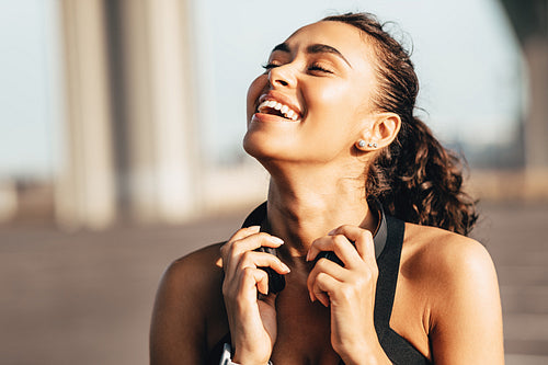 Happy female runner with headphones around her neck