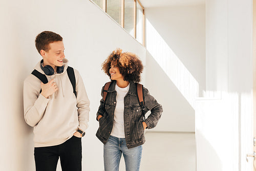 Classmates walking in corridor. Girl and boy looking at each other in college.