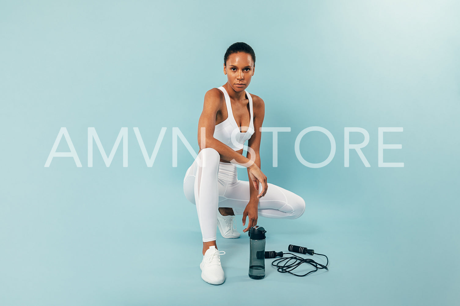 Young fit woman resting after training over a blue background in a studio looking at camera	