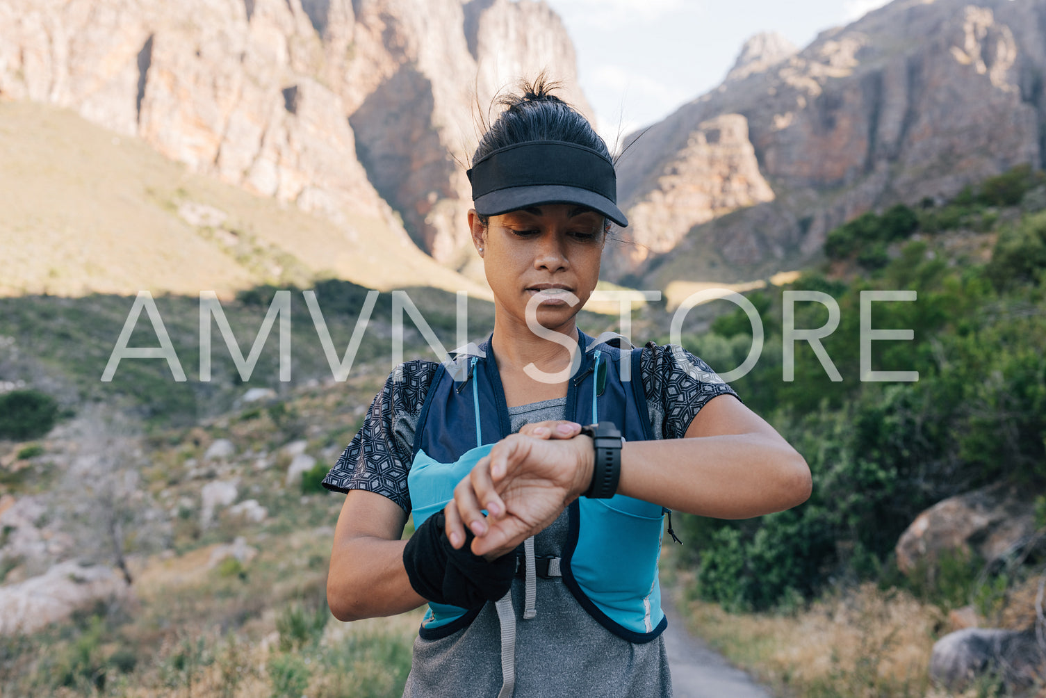 Young woman hiker checking smart watch while standing in valley