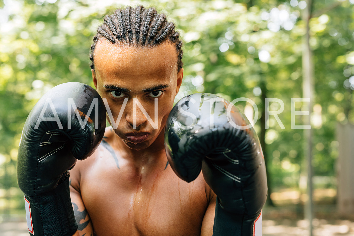 Close up portrait of a sweated kickboxer with gloves and mouth guard looking at the camera	