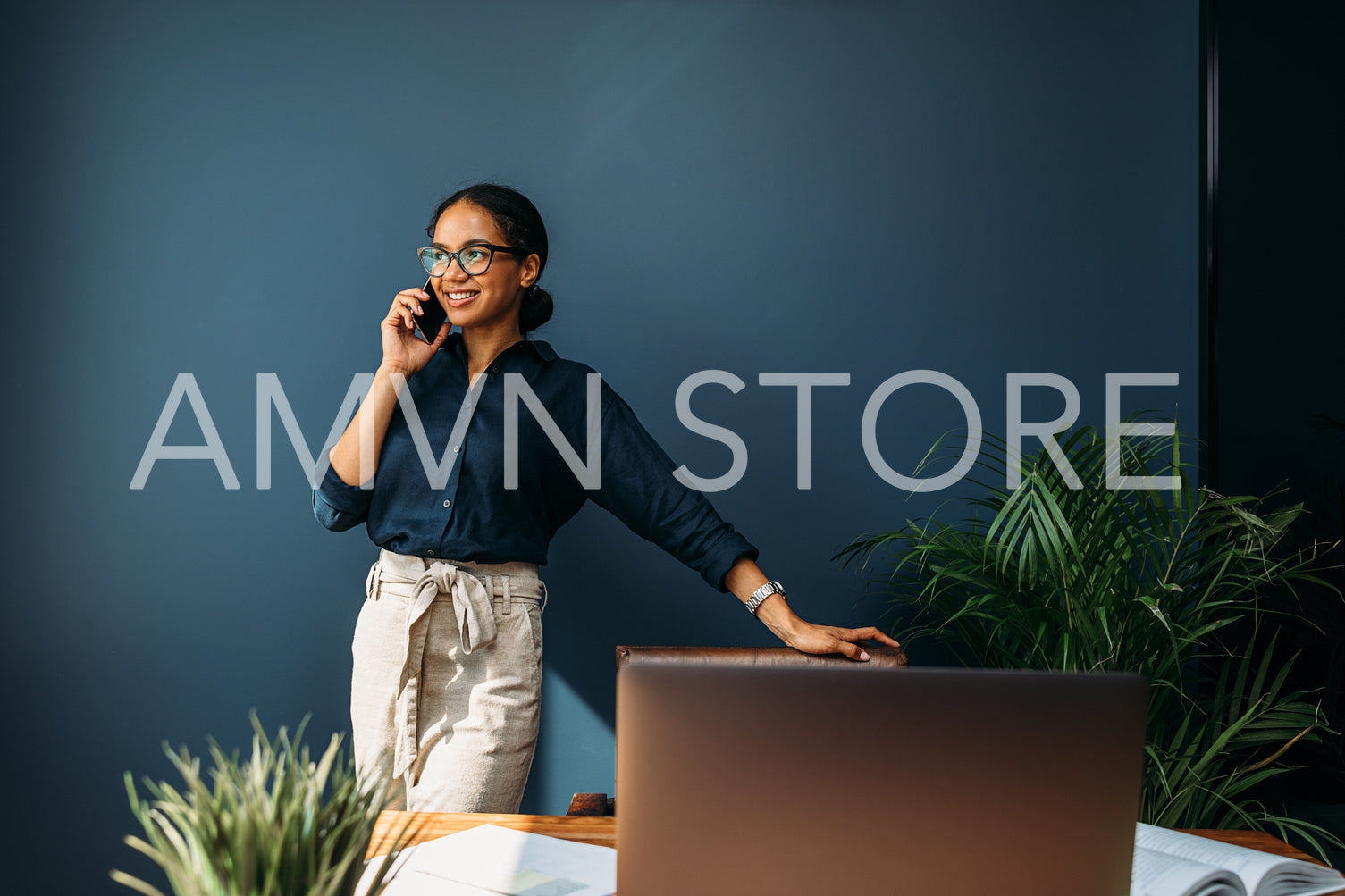 Happy entrepreneur leaning to a chair and looking away while talking on mobile phone	