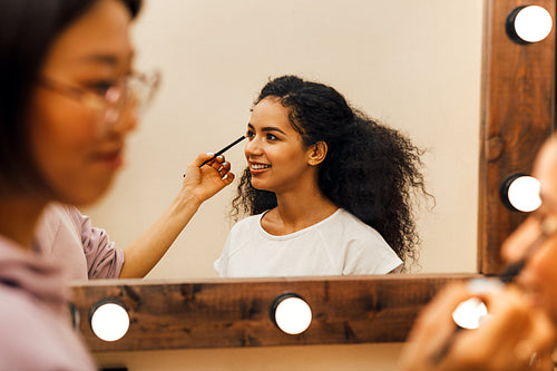 Side view of a makeup artist preparing model for a photo shoot