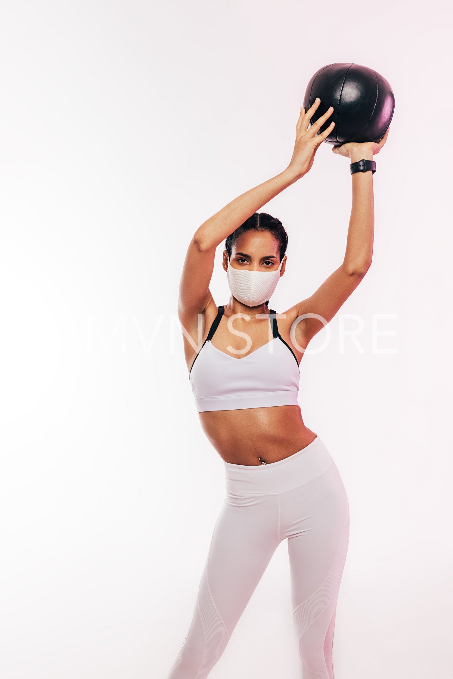 Young sportswoman wearing face mask holds the medicine ball 