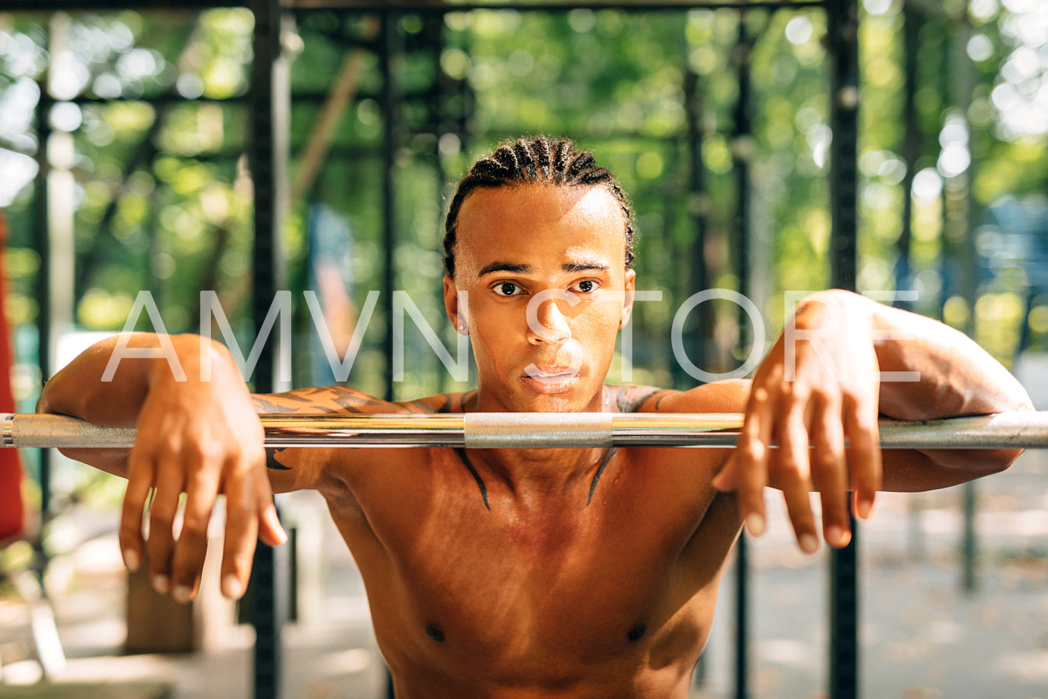 Portrait of a young sportsman resting during exercises leaning on a weight bar	