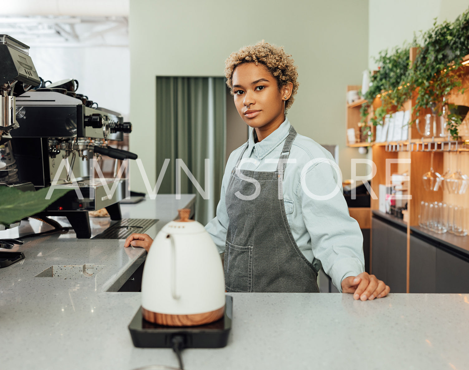 Young barista in a coffee shop. Young female with short hair working as a barista.