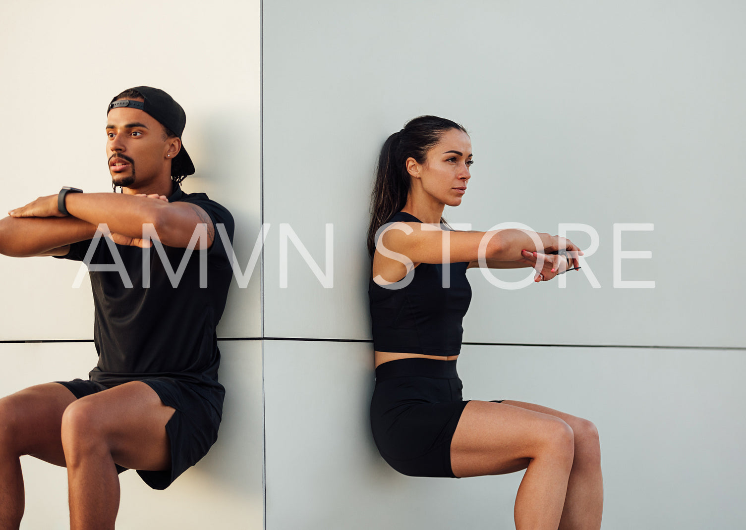 Fitness couple exercising together. Man and woman doing wall squat outdoors.