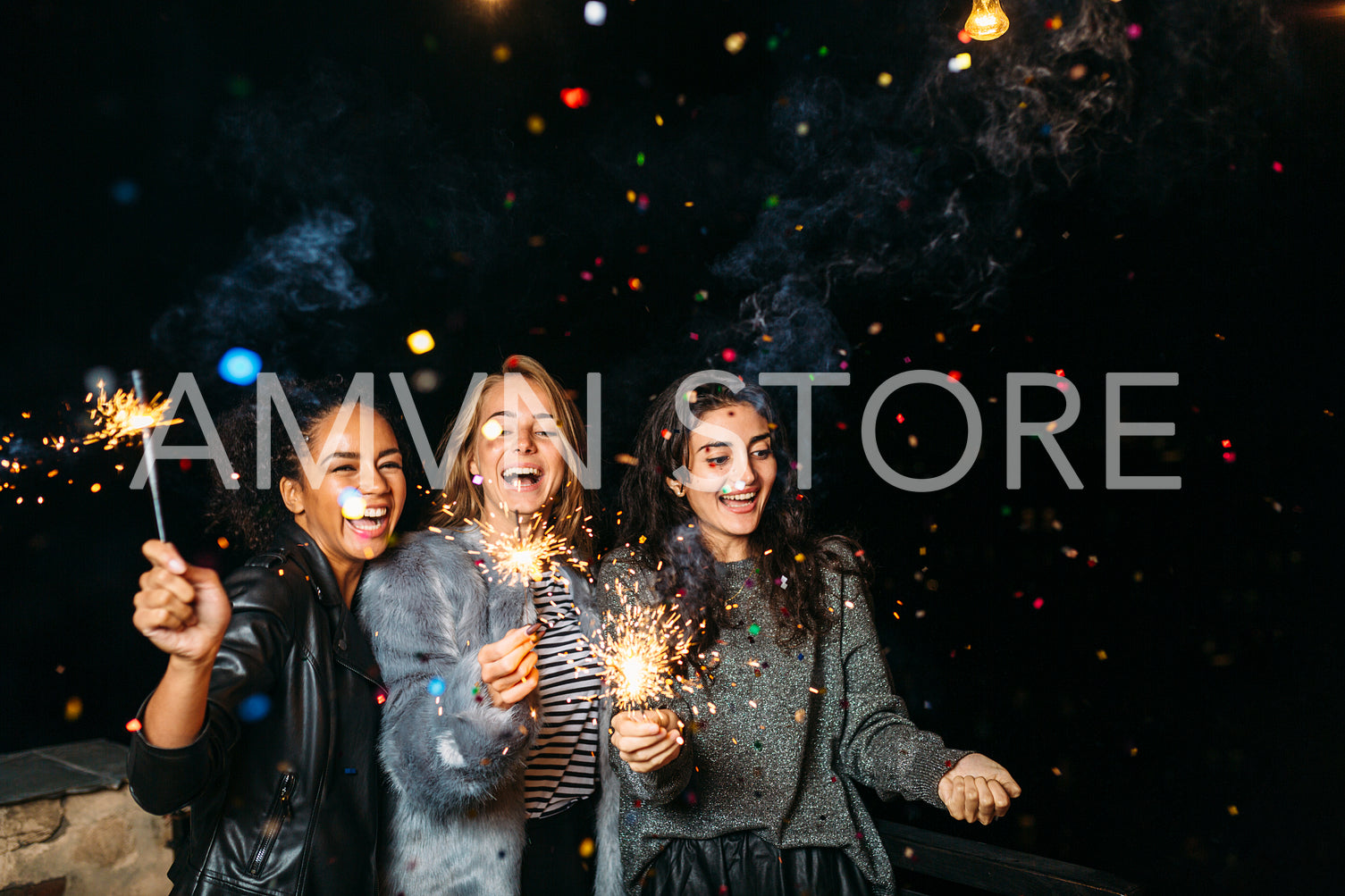 Three happy women having fun with sparklers. Outdoor party.	