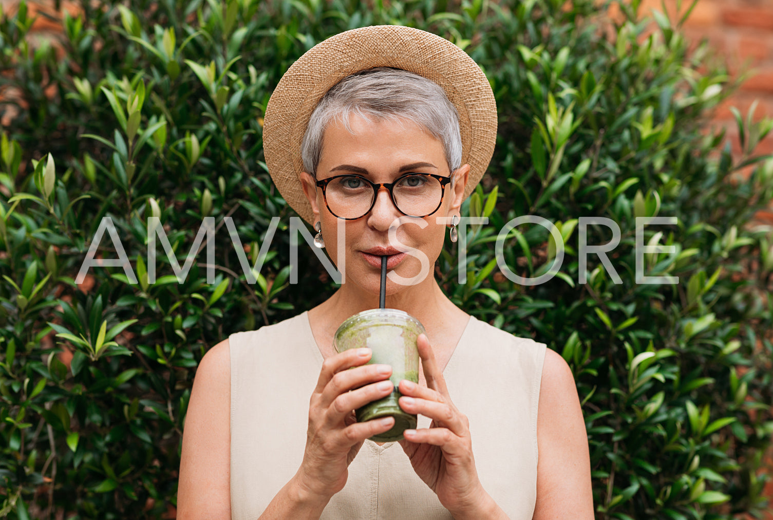 Stylish mature woman with grey hair drinking matcha latte outdoors