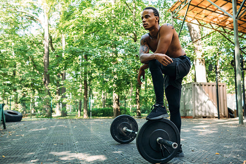 Bare-chest bodybuilder resting after deadlifting exercises