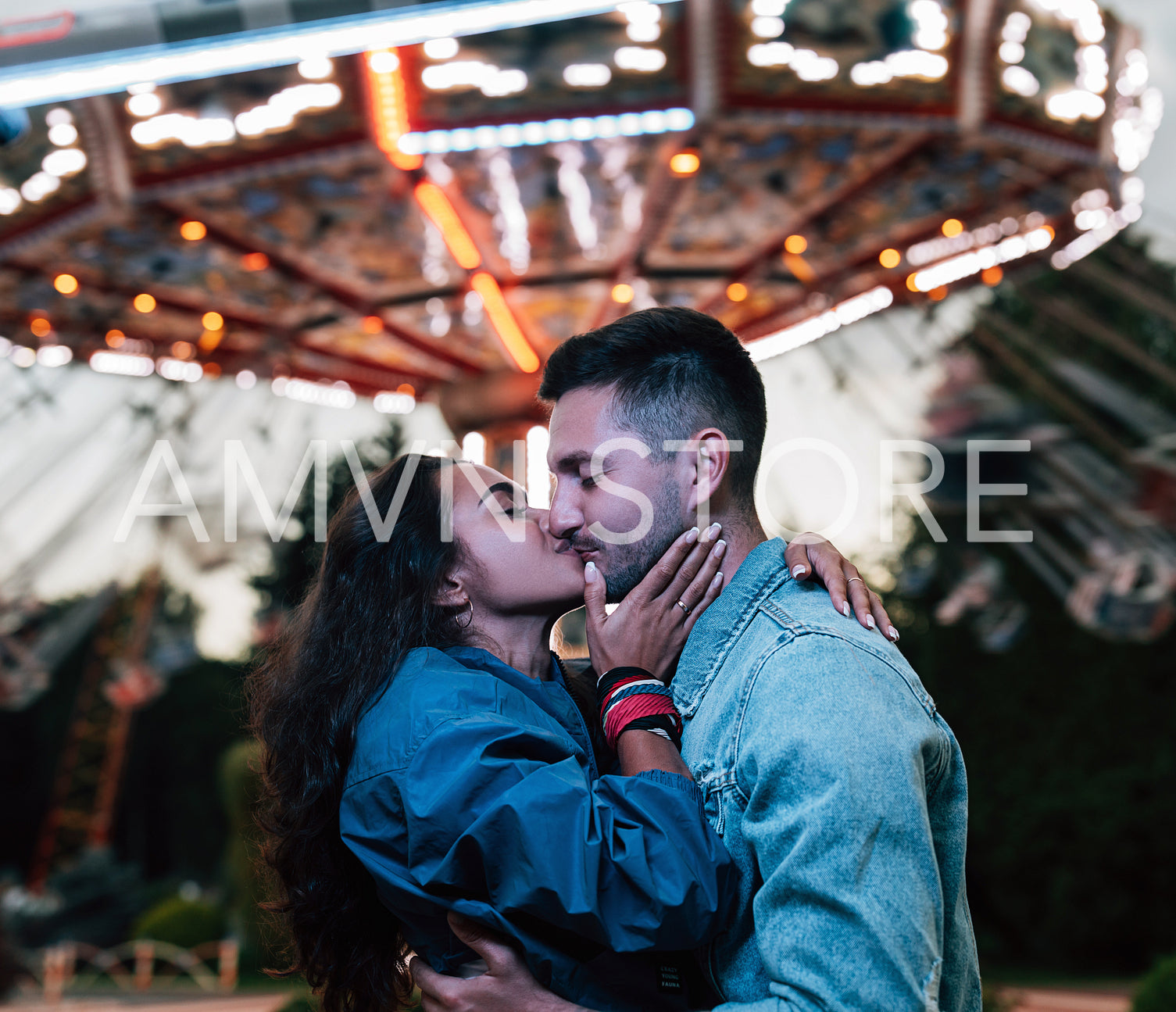 Side view of a young couple kissing during festival against carousel