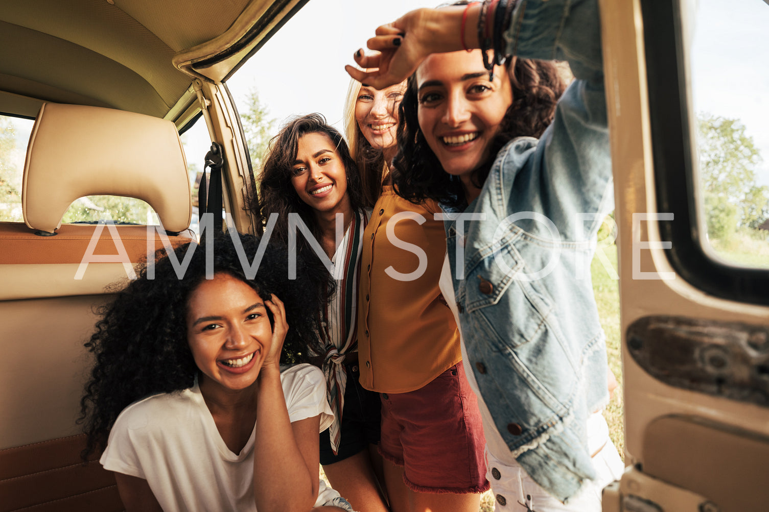 Four beautiful women looking at camera while sitting in minivan