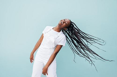 Happy woman with long braided hair having fun against a blue wall outdoors