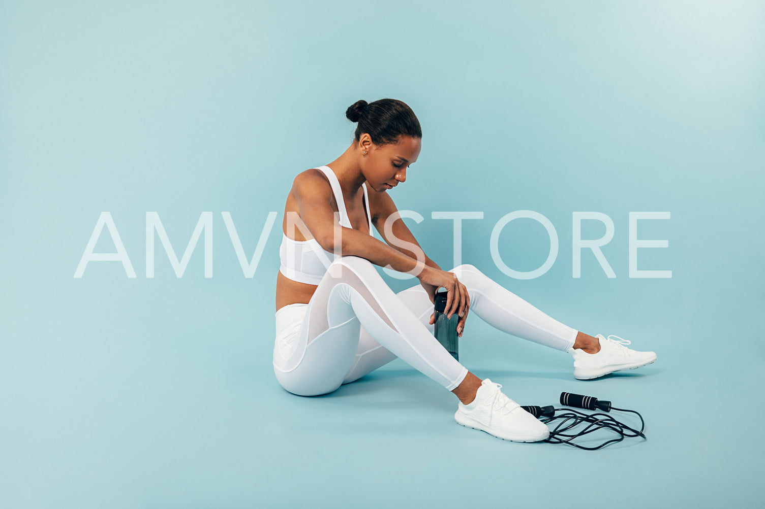 Tired woman sitting on blue background in studio after training	