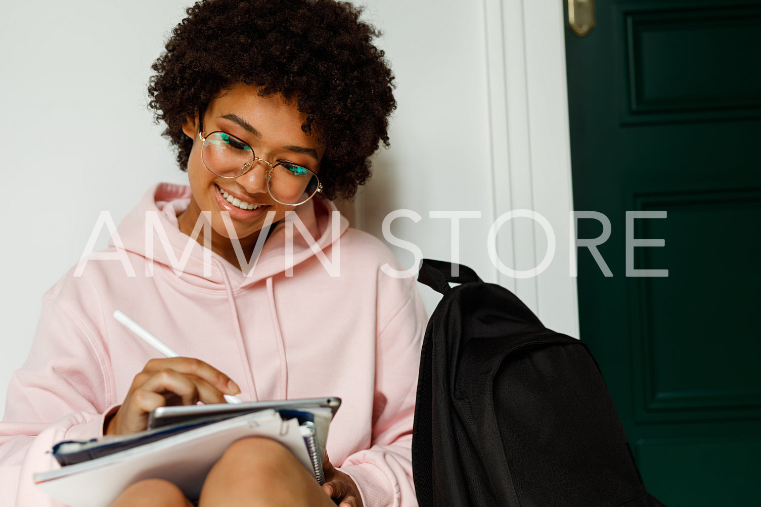 Female student sitting on a floor in campus and writing on digital tablet with stylus	