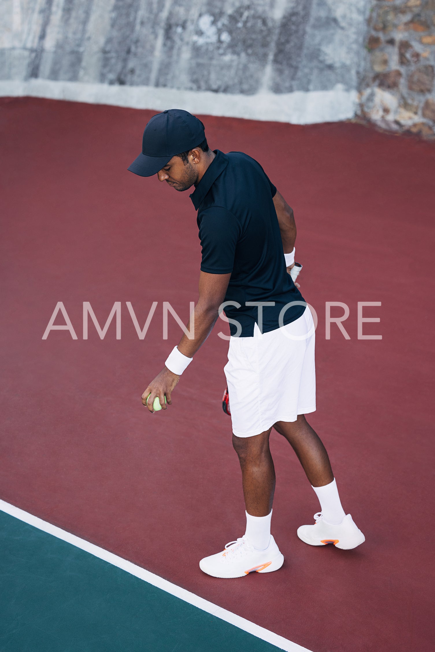 Young man bouncing the ball at the baseline on the hard court for the serve