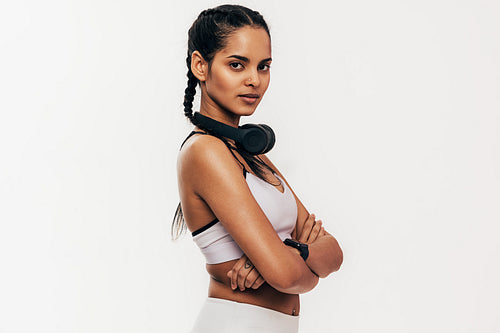 Confident woman in sportswear standing against white background with crossed arms