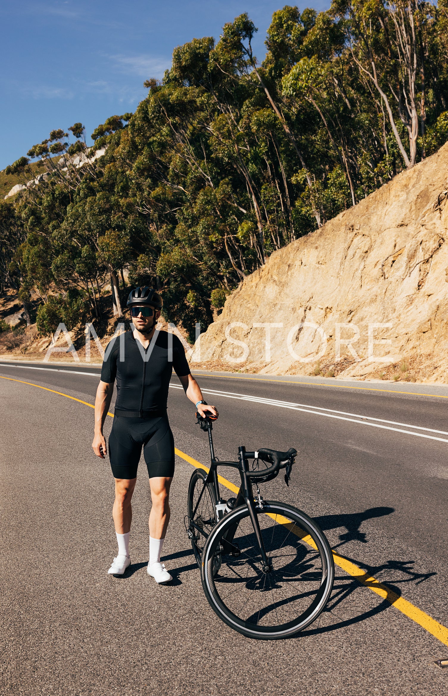 Professional cyclist with his road bike on an empty road. Man walking with bicycle.