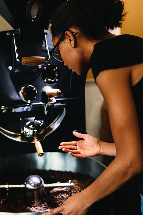 Young woman controlling process of a roasting coffee