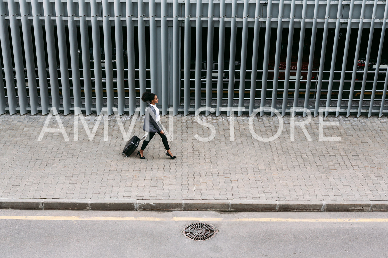 High angle view of businesswoman walking with suitcase near parking garage	