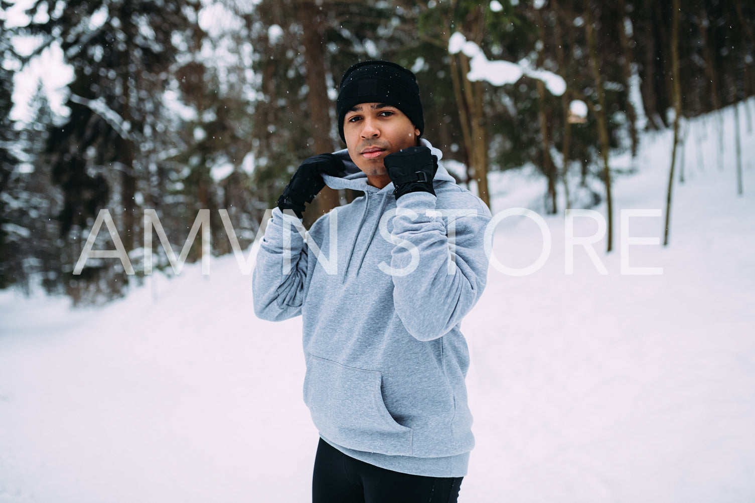 Young sportsman relaxing after training in snowy park	
