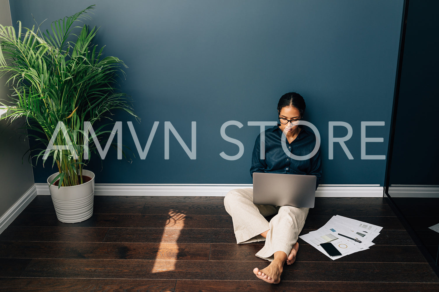 High angle view of businesswoman sitting on floor in living room. Young woman managing her online business from home.	