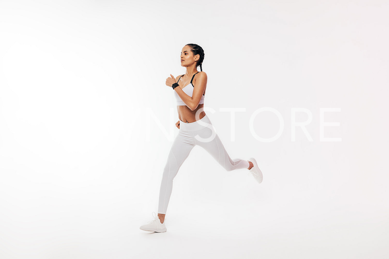 Fitness woman in sportswear running over white background in studio