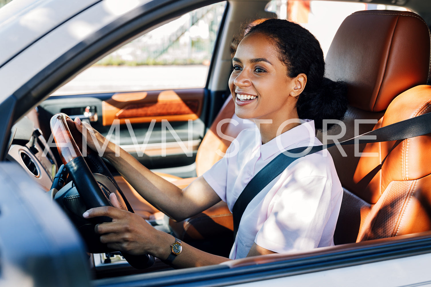 Smiling woman driving looking out a car window. Happy woman holding a steering wheel in the vehicle.	