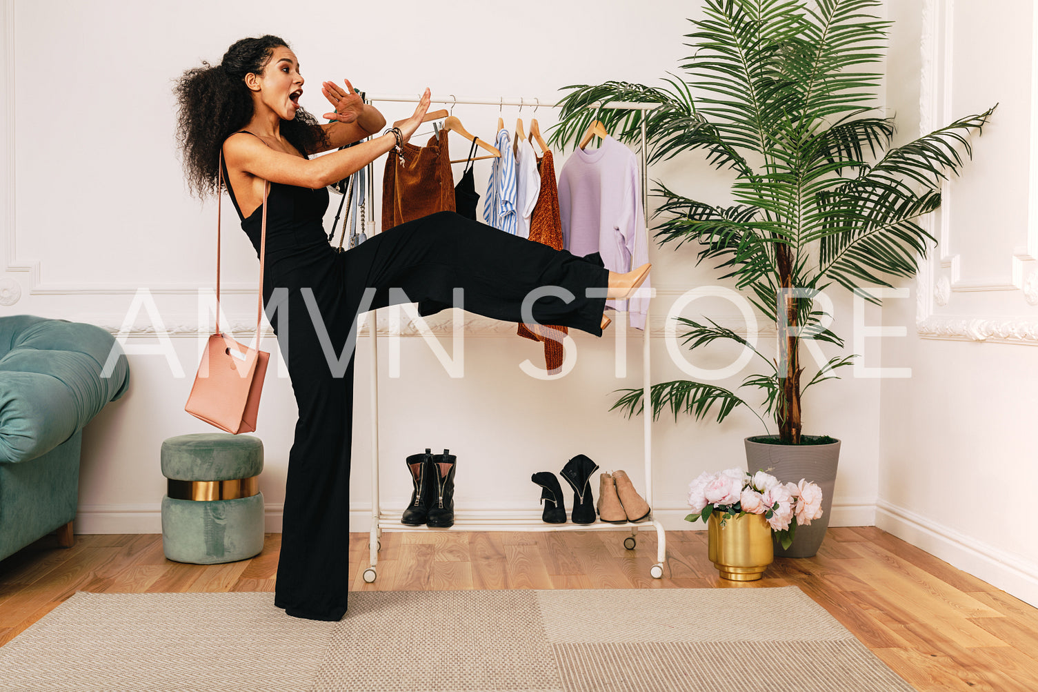 Fashion stylist laughing in studio at clothes rack	