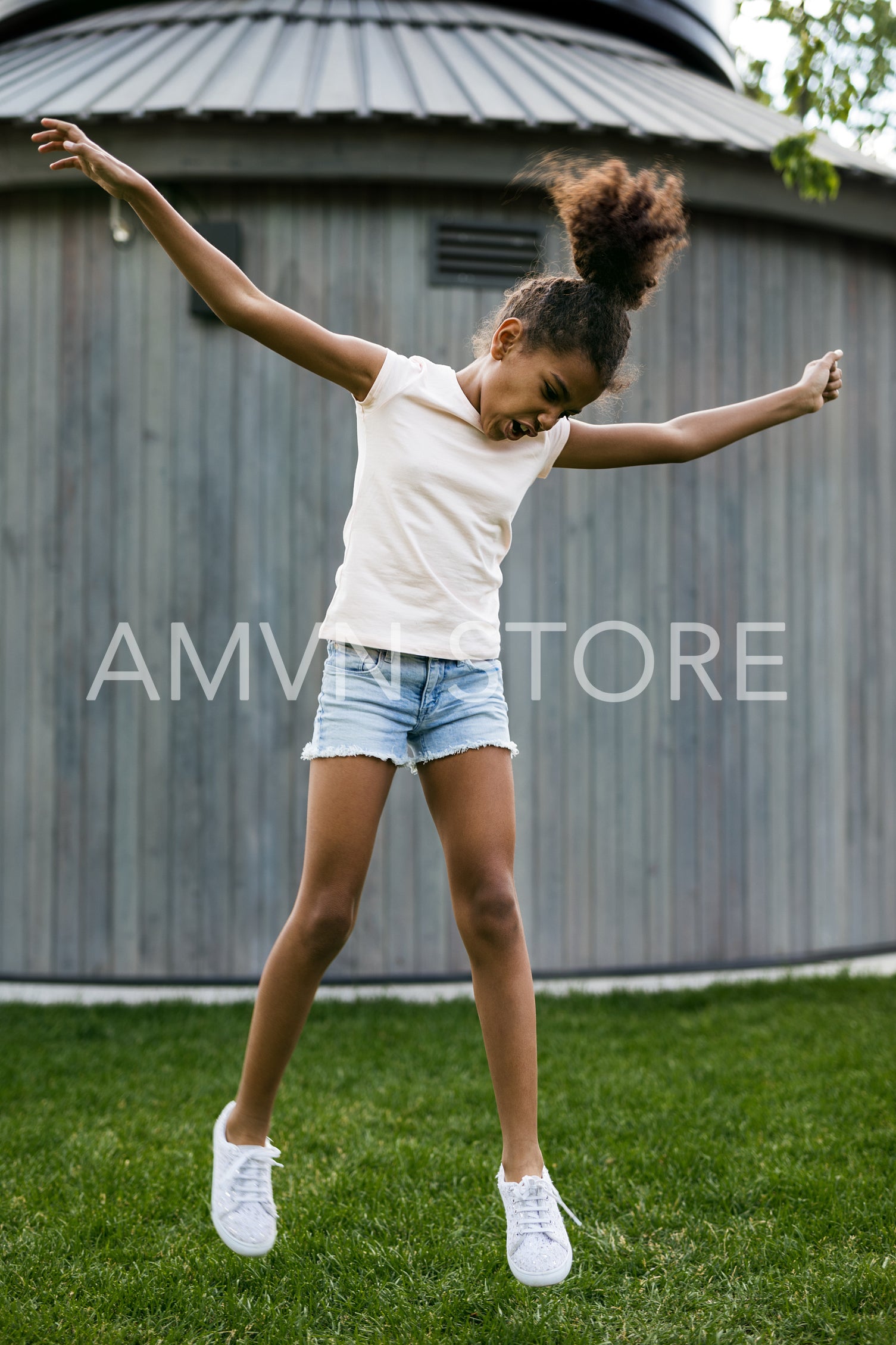 Cheerful girl jumping on grass at backyard