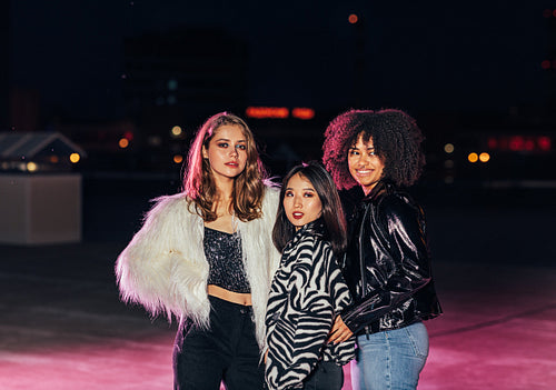 Three beautiful gilrs standing on roof at night and looking away